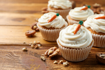 Delicious carrot cupcakes and walnuts on wooden table, closeup. Space for text