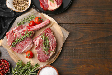 Pieces of raw beef, tomatoes and spices on wooden table, flat lay. Space for text