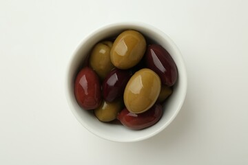Tasty marinated olives in bowl on white table, top view