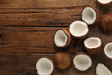 Halves of fresh coconuts on wooden table, flat lay. Space for text