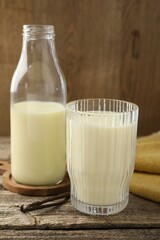 Delicious vanilla milk and pods on wooden table