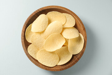 Tasty potato chips in bowl on light blue background, top view