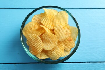 Tasty potato chips on blue wooden table, top view