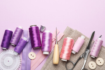 Different sewing supplies on lilac background, flat lay. Space for text