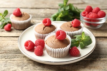 Delicious muffins with raspberries and mint on wooden table, closeup