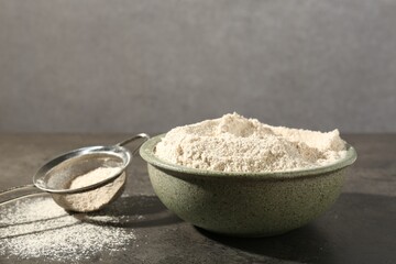 Brown rice flour and sieve on grey table. Space for text