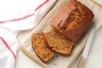 Homemade carrot cake with nuts and knife on white wooden table, top view