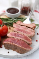 Delicious sliced beef tenderloin with different degrees of doneness, tomatoes and spices on table, closeup