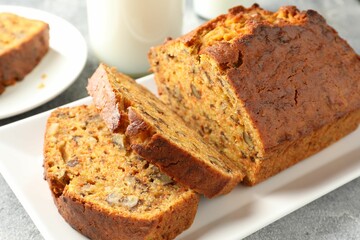 Cut homemade carrot cake with nuts and milk on grey table, closeup
