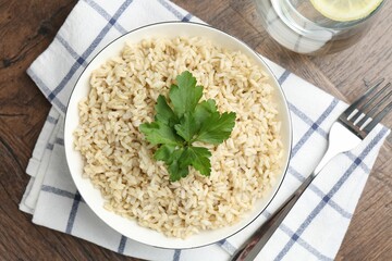 Delicious brown rice with parsley served on wooden table, top view