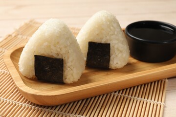 Rice balls (onigiri) and soy sauce on table, closeup. Traditional Japanese dish