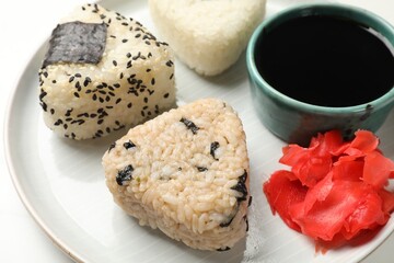 Rice balls (onigiri), soy sauce and pickled ginger on table, closeup. Traditional Japanese dish