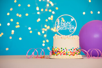 Tasty bento cake with colorful sprinkles, topper and balloon on table against light blue background, space for text. Bokeh effect