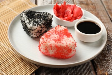 Tasty tobiko onigiri (Japanese rice balls) served on wooden table, closeup