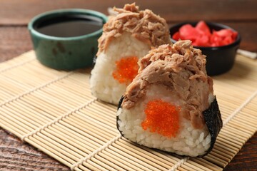Tasty onigiri (Japanese rice balls) with tuna served on wooden table, closeup