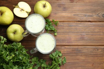 Healthy parsley drink in glasses, leaves and apples on wooden table, flat lay. Space for text