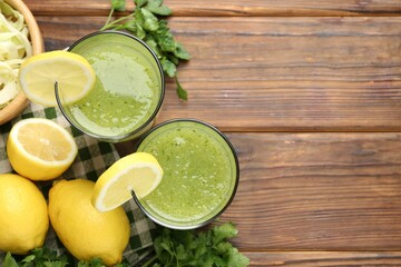 Healthy parsley drink in glasses, lemons and cabbage on wooden table, flat lay. Space for text