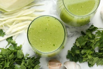 Healthy parsley smoothie, garlic, cabbage and leaves on white marble table, flat lay