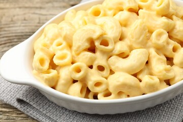 Delicious pasta with cheese sauce in baking dish on table, closeup