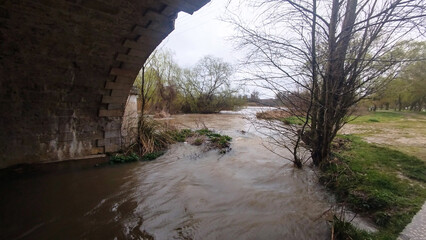 Crecida de río con barro pasando por debajo de un puente moderno en Burgos, España