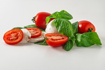 fresh mozzarella, tomatoes and basil leaves on a white surface caprese salad concept