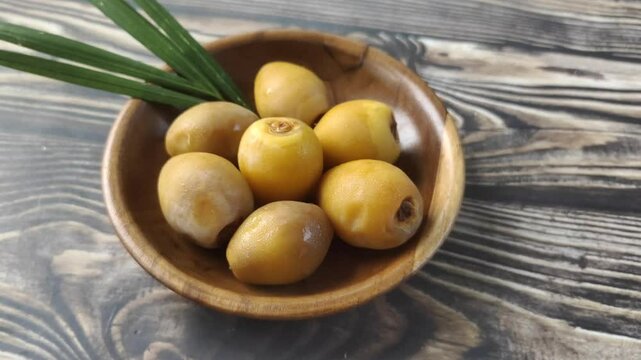 A group of fresh young dates or rutob dates or ruthob dates on a wooden plate on a wooden table.