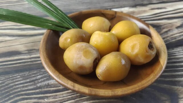 A group of fresh young dates or rutob dates or ruthob dates on a wooden plate on a wooden table.