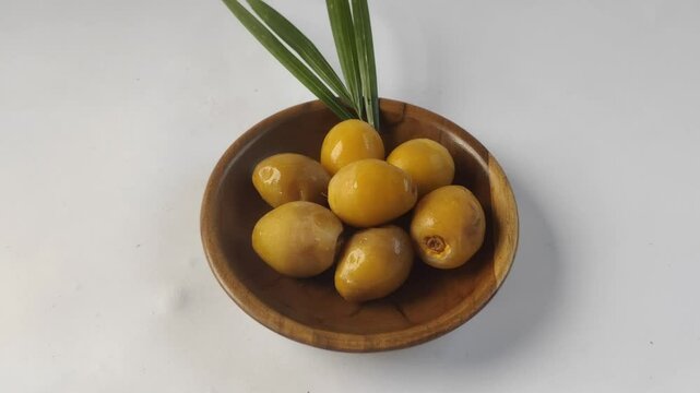 A group of fresh young dates or rutob dates or ruthob dates on a wooden plate with a white background.