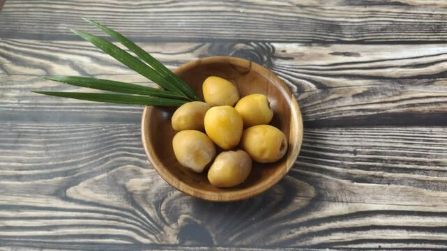 A group of fresh young dates or rutob dates or ruthob dates on a wooden plate on a wooden table.