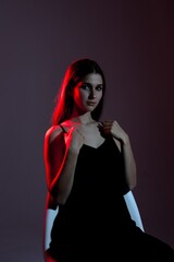 Portrait of a young woman sitting on a chair with dramatic lighting in a studio setting during a photoshoot
