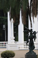 statue against the background of white columns and palm trees