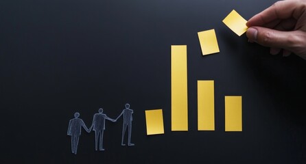 Hand arranging yellow sticky notes forming a declining bar graph with translucent figures.