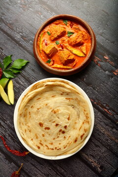 Kerala foods background- spicy coconut mango fish curry served with malabar porotta, parotta.