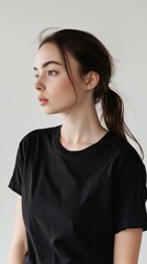 Fototapeta premium Young European and American Woman in Her 20s Wearing a Black T-Shirt Standing and Looking to the Side with a White Background