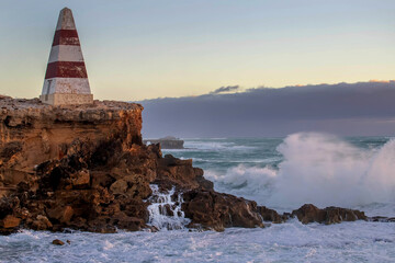 Historic Robe Obelisk stands tall on the rugged coastline of South Australia, surrounded by waves,...