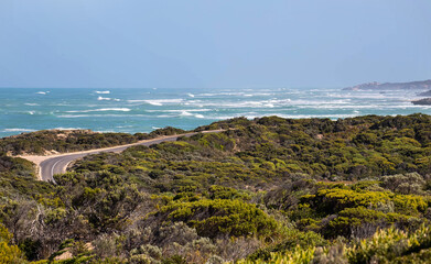 Coastal road curves past turquoise waters and rocky cliffs in South Australia, with a traffic...