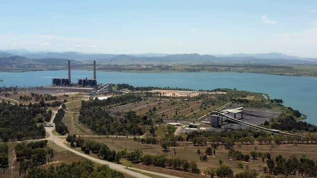 Green Hunter valley lake Liddell industrial site with storage of black coal and railroad.
