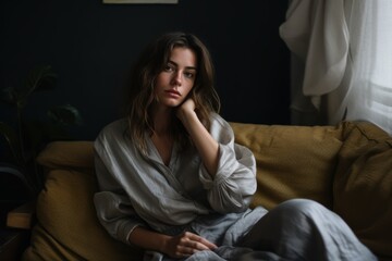 Obraz premium A woman is sitting on a couch with her arms crossed