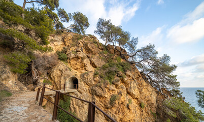 A rocky cliff with a tunnel leading to the ocean