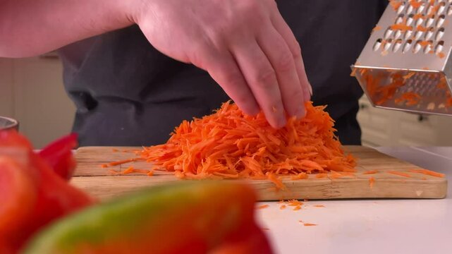 a man grates raw carrots in the kitchen, foreground