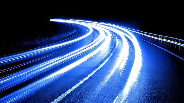 Blue light trails of cars on a highway curve at night.