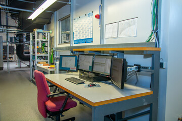 Industrial control room with multi-monitor workstation for real-time system analysis, data visualization, and process control in a high-tech engineering environment