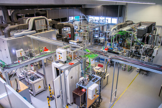 Wide view of advanced industrial automation laboratory with control panels, machinery, cable trays, and testing stations used for engineering research and factory system development.