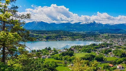 Panoramic view of Velden am Wörthersee, Carinthia, Austria. Serene Wörthersee lake, lush green landscapes, and surrounding hills and Karawanks mountain range, seen from the Hoher Kreuz viewpoint. © Chris