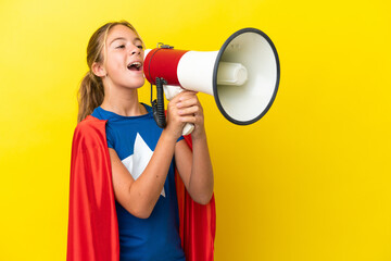 Super Hero little girl isolated on yellow background shouting through a megaphone