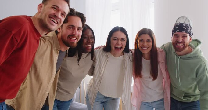 Happy overjoyed smiling multi ethnic friends group together, smiling diverse people standing close together, hugging, looking at camera, smiling, laughing for team cooperation, relationships amusement