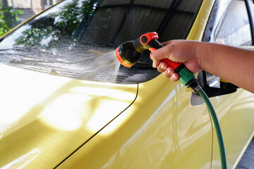 a man's hand is holding a water spray to rinse and wash the car
