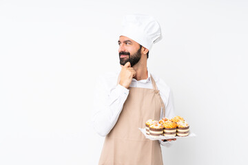 Young man holding muffin cake over isolated white background looking to the side