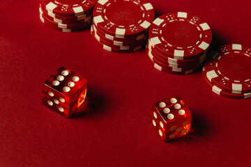 Two vibrant red dice with white dots rest near stacks of red poker chips on a deep red table, suggesting a lively game night atmosphere. The winning combination in craps is two sixes