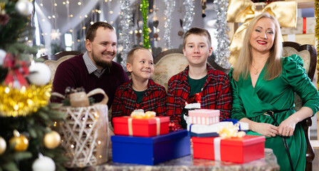 Portrait of happy family with two children celebrating Christmas next to Christmas tree